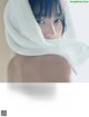 A woman wrapped in a white towel is looking at the camera.